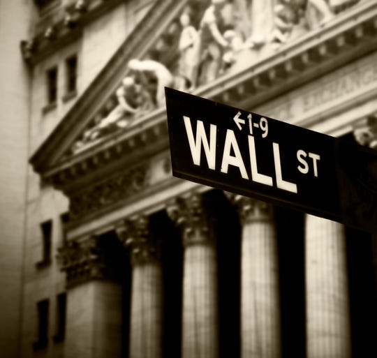 Wall Street sign with New York Stock Exchange behind.