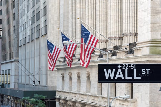 Wall Street street sign in front of a building with American flags