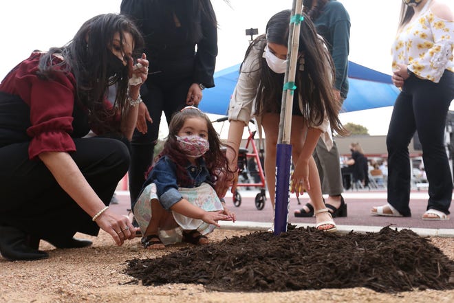 Lisa Soria, from left, Violet Franco and Leah Najera help plant a tree in memory of Leobardo Soria and his wife, Rosie Soria, on April 27 at Carroll T. Welch Elementary in Horizon City, Texas, where Leobardo was a security guard. Leobardo and Rosie died of COVID-19. The Clint Independent School District honored three employees who passed away during the pandemic in memorial services that week.