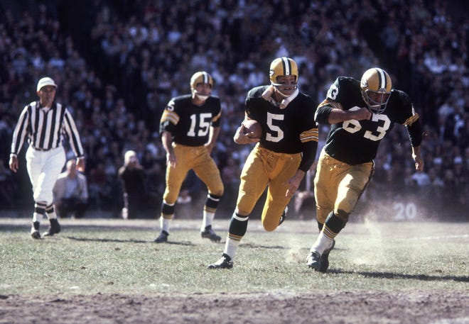 Green Bay Packers running back (5) Paul Hornung follows the blocking of guard (63) Fuzzy Thurston after taking the handoff from (15) Bart Starr during the 1964 season.