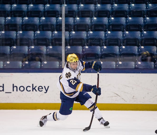 Notre Dame’s Max Ellis (21) shoots during the Michigan at Notre Dame NCAA hockey game Thursday, Jan. 21, 2021 at the Compton Family Ice arena in South Bend.
