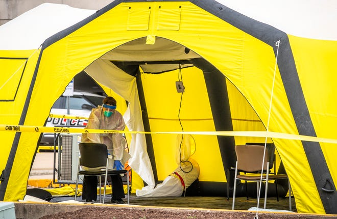 A medical worker cleans a seat on March 20 in a yellow tent set up to screen potential COVID-19 patients at IU Health Bloomington Hospital. The tents were temporary structures as part of COVID-19 screening. (Rich Janzaruk / Hoosier Times)