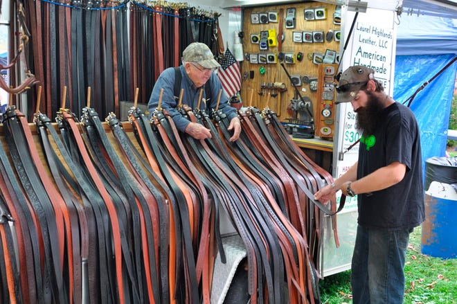 Ron Sollosi, Confluence, looks at handmade leather belts Friday at Laurel Highlands Leather co-owner Wayne McLaughlin's booth during the 29th annual PumpkinFest in Confluence Borough. Staff photo by Eric Kieta