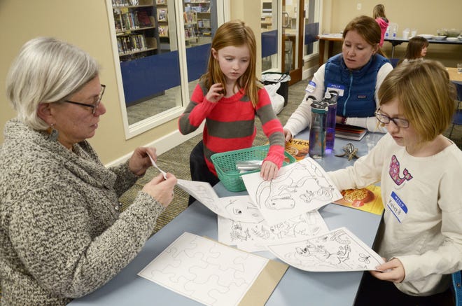 Valerie Meyerson, director of the Petoskey District Library, (left) does a craft with the Buchanan family during a Family Literacy Night, a part of the Growing Readers Together program.