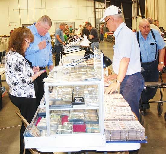 Individuals check the wares of one of the 21 dealers who rented 40 tables for the South Dakota Stamp &amp; Coin Show held in Watertown last weekend.