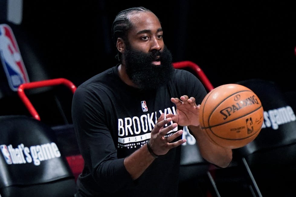 Brooklyn Nets guard James Harden, who has been out with a hamstring injury, takes the ball from a trainer while warming up before Game 5 of the team's second-round NBA basketball playoff series against the Milwaukee Bucks, Tuesday, June 15, 2021, in New York. (AP Photo/Kathy Willens)