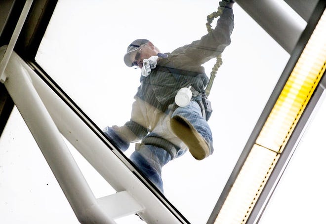 A window washer cleans windows on the slanted glass roof of the DoubleTree hotel building in downtown South Bend this week. SBT Photo/ROBERT FRANKLIN