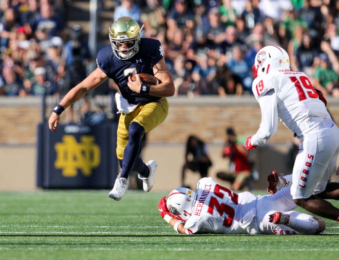 Notre Dame QB Brendon Clark (7) jumps over a tackle by New Mexico’s Johnny Hernandez (32) during the Notre Dame-New Mexico game, Saturday, September 14, 2019, at Notre Dame Stadium in South Bend.