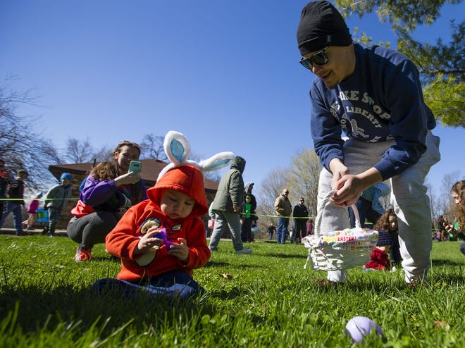 Javier Galicia, helps his 1-year-old son, Haven, hunt for eggs. Tribune Photos/MICHAEL CATERINA