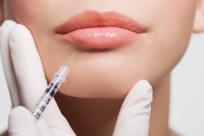 A syringe pointing at a person's lips.