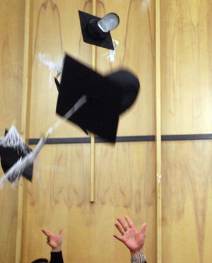 Graduates toss their mortar boards in the air during a graduation ceremony.