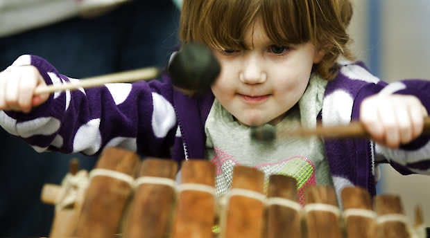 Ellie Warren, 4, pounds musical wooden blocks Saturday at the Lotus Blossoms Bazaar at Binford Elementary School. David Snodgress | Herald-Times