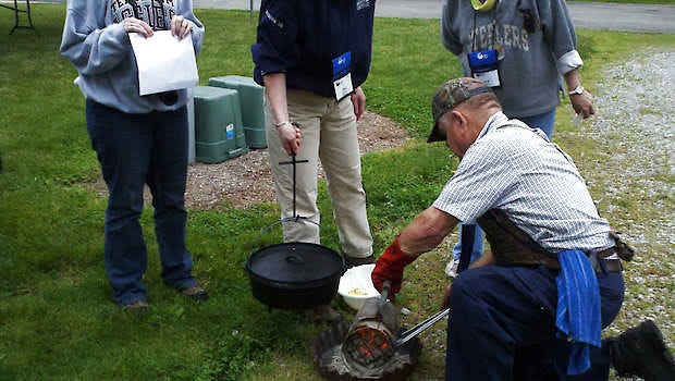 Jim Mahoney pours hot coals ready to be placed under a Dutch oven during a cooking demonstration at the Becoming an Outdoors Woman Workshop weekend in 2012 at Ross Camp near West Lafayette. Mahoney and his wife, Nancy, of Columbus, teach Dutch oven cooking techniques at various conventions and events across the United States.Brooke McCluskey | Courtesy photo