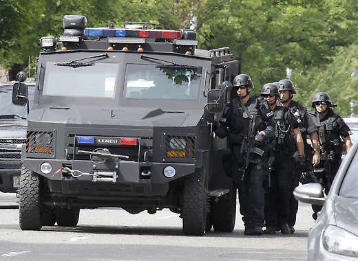 A SWAT team uses a vehicle for protection as they walk to a house in the Seattle neighborhood where a shooting took place Wednesday.Ted S. Warren | Associated Press