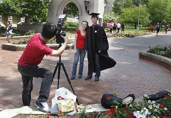Yuwei Wu, right, poses for a photo with his wife Shan-Hui Lin, while Chuan-Yih Yu takes a photograph at Indiana University’s Sample Gates. Wu is getting his degree in informatics this weekend. Jeremy Hogan | Herald-Times