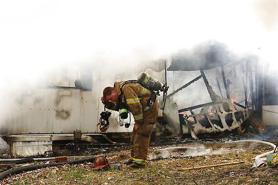 Paramedic student Amy Wilcher, left, and medic Dennis Duncan, right, check on Ellettsville Fire Department Capt. Kevin Patton, who became exhausted Wednesday while fighting a mobile home fire at 5901 W. Cowden Road. Jeremy Hogan | Herald-Times