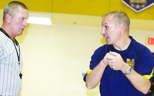 Mooresville wrestling coach Zach Errett discusses moves with an official during a match in the Curry Center Gymnasium. File photo by Steve Page.