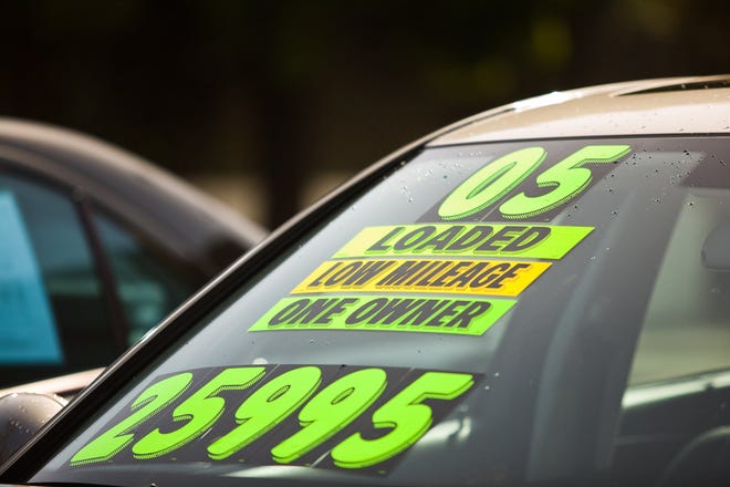 Advertising information on a used car's windshield at a dealership.