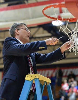 Patriot head coach Roger Fleetwood triumphantly trims his piece of the net after the sectional championship win. (Rebecca Tabor / Spencer Evening World)