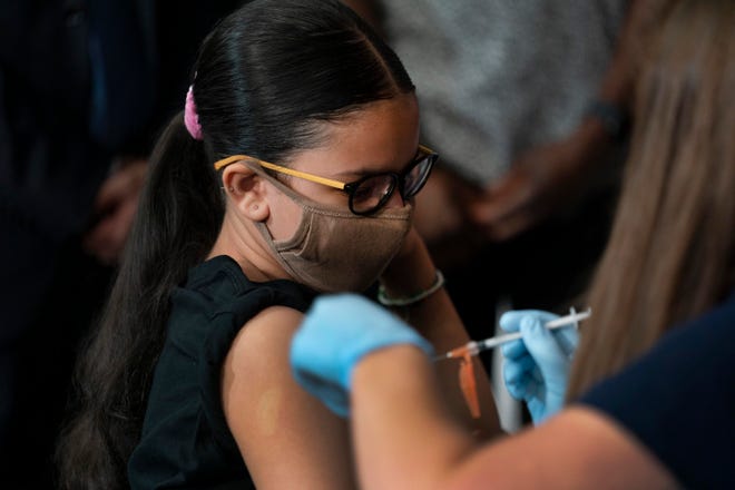 Giret Madina, 14, gets a dose of the Pfizer COVID-19 vaccine at Lehman High School in New York on Tuesday. Amid lagging vaccination rates across the country, some public health officials say that full approval of the vaccines by the U.S. Food and Drug Administration would go a long way in boosting rates.