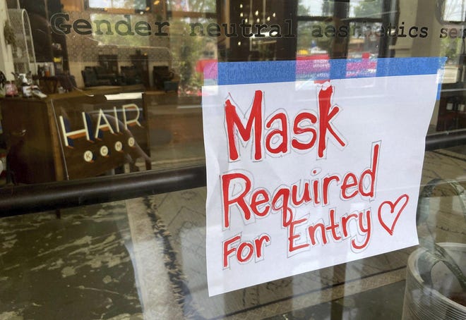 A sign at a Kansas City, Missouri, hair salon this month informs patrons that masks are required inside. The recent COVID-19 surge has prompted the return of restrictions to try to stop the spread.