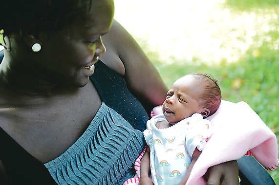 Nok Duany Bassey, whose family moved to Bloomington from Sudan in 1984. She is holding her 3-week-old daughter, Mai.
