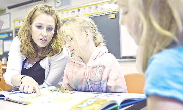 NEEDMORE -- As Vanessa Conner reads, first-grade teacher Morgan Riggs helps Hannah Heaton with word recognition during class on Tuesday. (Times-Mail / RICH JANZARUK)