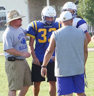 MITCHELL — Mitchell High School varsity football Coach John Edge, left, confers with players and coaches during scrimmage action between the Mitchell varsity squad and the BNL JV Thursday. (Times-Mail / GARET COBB).
