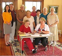 BEDFORD — Mary Jo Cannedy, front row, left, president of the Lawrence County Art Association, signs a lease agreement for the Wiley House with Bedford Revitalization Inc. President Susan Gales. Also at the signing were Jamie Medlock, Gene McCracken, Oakleigh Westfall, Mary Anderson, Robert Allen, Dottie Sherwood, Imogene Myers and Mary Margaret Stipp, from left. ((Times-Mail / JEFF ROUTH)