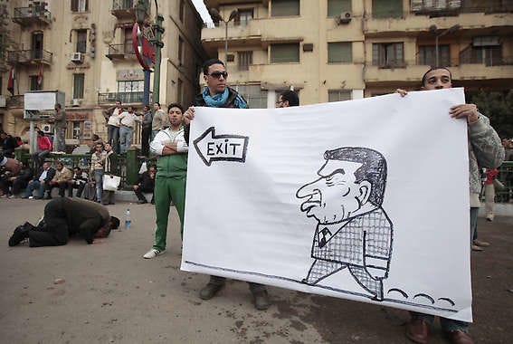 Protesters hold a banner next to people praying Sunday during a demonstration in Cairo, Egypt.Lefteris Pitarakis | Associated Press