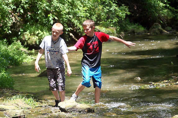 MITCHELL — Garrett Ramsey, left, and Coby Byers enjoy the Spring Mill Creek Monday. (Times-Mail / GARET COBB)