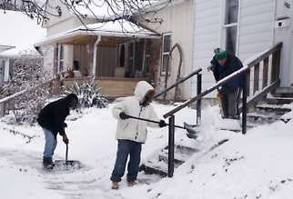 Left to right, Peng Campbell, Molin Champaigne and Simon Ladd shovel snow today from the entrance of a rental property at 920 W. Sixth St. Jeremy Hogan | Herald-Times
