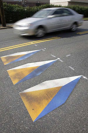 A car passes near a three-dimensional image of speed bumps on a road Friday in Philadelphia.Matt Rourke | Associated Press