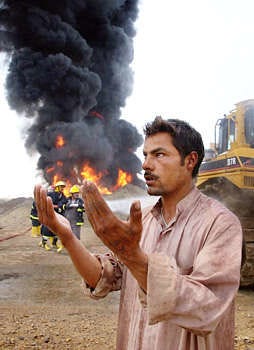 A local resident offers prayers near firefighters who had been working all night try to put out a pipeline fire Thursday near Diwaniyah, Iraq. Alaa al-Marjani | Associated Press