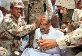 Iraqi soldiers wash the face of a recently released prisoner, Abdul-Kader of Ramadi, at the main bus station Thursday in Baghdad, Iraq. More than 450 prisoners were released Thursday as part of Iraqi Prime Minister Nouri al-Maliki\'s national reconciliation efforts, according to the U.S. military. Khalid Mohammed | Associated Press.