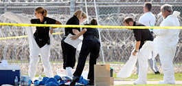 Tallahassee Police Department forensics officers suit up to collect evidence outside the Federal Detention Center following a triple shooting that left two people dead and one injured Wednesday in Tallahassee, Fla. Mike Ewen | Associated Press
