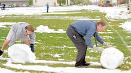 Gary Grey, athletic director at Montana State, Billings, and his son Daneson Grey roll giant snowballs Wednesday to clear the school\'s soccer field of snow before a game with Dallas Baptist in Billings Mont. The heavy overnight snow also downed trees and powerlines. Bob Zellar | Billings Gazette | Associated Press
