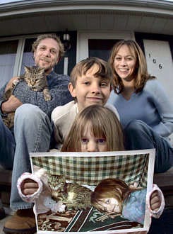 Abbey Herndon, 5, foreground, sits with her family, from left, stepfather, Donny McElhiney, cat Tori, brother Nick and mother, Lesley McElhiney, as she holds a photo of herself and the family\'s missing cat, Emily, at their home in Appleton, Wis., Oct. 27. Emily, one of three cats owned by the family, escaped from their home a little over four weeks ago and became an accidental stowaway to Nancy, France. Sharon Cekada | Associated Press