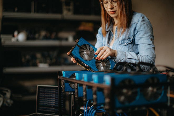 A young woman assembles a computer to mine Bitcoin.