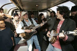 Musician Arlo Guthrie, left on guitar, plays "City of New Orleans" with other musicians aboard Amtrak\'s City of New Orleans train, Thursday near Hammond, La. "Arlo &amp; Friends" will travel for 12 days performing along the way to benefit the small musical venues in the train\'s namesake city that were devastated by Hurricane Katrina. Jacqueline Larma | Associated Press