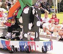 One of the crowd favorites at Monday\'s Linton Freedom Festival parade was Coco the cow, ridden by Fred Eads and towed by his wife, Diana, of Galveston. The Eadses belong to a Christian clowning organization and have been going to parades such as this for 12 years. Staff photo by Monty Howell.