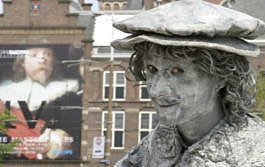 A street artist, dressed like Rembrandt, poses in front of Rijksmuseum in Amsterdam, Netherlands. The Rembrandt-Caravaggio exhibition, along with the celebration for the Rembrandt\'s 400th birthday, has exceeded expectations and bolstered first-quarter earnings, drawing 200,000 people from all over the world to the museums in Amsterdam during a five-week period. The increase in tourism also has affected hotels and their bookings as visitors make the trek to see the celebrated pieces. Alex Kals | Associated Press