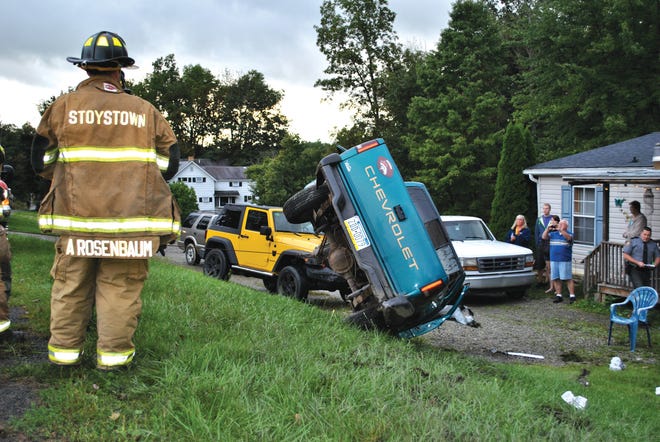 Stoystown firefighter Adam Rosenbaum watches a tow truck flip a pickup truck after an accident Friday. The vehicle, traveling on Whistler Road, flipped around 5 p.m. and landed in David Golden’s yard in Stoystown. The driver was taken to Conemaugh Memorial Medical Center, Johnstown, for injuries after being ejected from the vehicle. Golden said many drivers have wrecked near his house, usually ending up in an empty field. This was the first to end up in his front yard, he said. Stoystown and Hooversville fire departments, Stoystown and Hooversville emergency services and state police responded to the scene. A police report was not available Friday night.