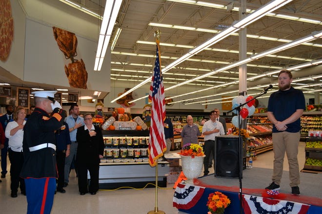 Marine Master Sgt. Nathan Hostetter salutes the American flag while Somerset Wal-Mart Supercenter employee Dylan Dively sings the national anthem. Staff photo by Vicki Rock