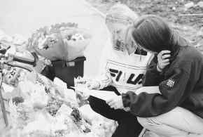 Two unidentified young women read tributes beside flowers outside the Quinn family house in Ballymoney, Northern Ireland, Monday. Three of the four Quinn boys were killed in a sectarian arson attack on the house early Sunday. AP Photo