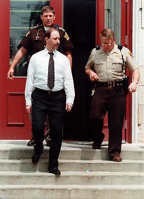 Randall Hubbard walks out of the Morgan County Courthouse in Martinsville with reserve deputy Bob Jones behind him and jail commander Guy Fogleman on the right. Hubbard, charged with murder, is wearing an electrical shock band under his shirt instead of chains and cuffs, which have previously been used to keep a prisoner from escaping. Staff photo by Jeremy Hogan
