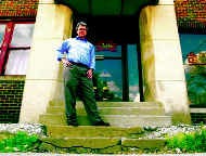 Phil Stafford, executive director of the Evergreen Institute on Elder Environments, stands on the front steps of the old Coca-Cola building at 318 S. Washington St. The Evergreen Institute plans to remodel the building to create affordable housing choices for the elder community in Bloomington. Staff photo by Chris Howell