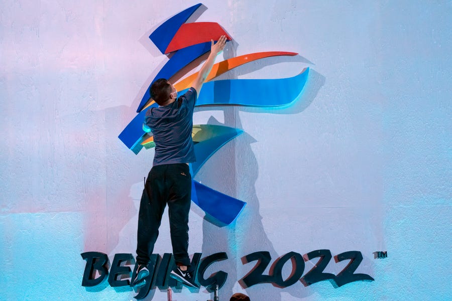 A crew member leaps to fix a logo for the 2022 Beijing Winter Olympics before a launch ceremony to reveal the motto for the Winter Olympics and Paralympics in Beijing, Friday, Sept. 17, 2021. Organizers on Friday announced "Together for a Shared Future" as the motto of the next Olympics, which is scheduled to begin on Feb. 4 of next year. (AP Photo/Mark Schiefelbein)