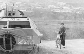 A young boy walks his bicycle past the ruins of an armored personnel carrier outside the village of Nakhichevanik in eastern Nagorno-Karabakh, inside Azerbaijan, March 13. Life is returning to normal in the ethnic Armenian enclave four years after the end of its war of secession from Azerbaijan. But Nagorno-Karabakh\'s status remains unclear, and peace negotiations are stalled. AP photo