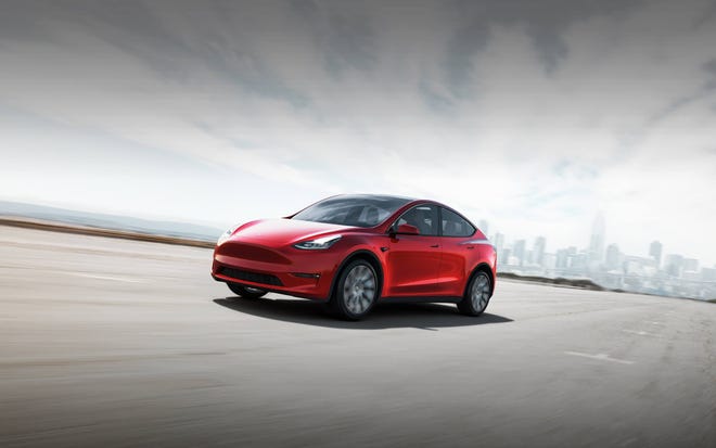Tesla Model Y on an open lot with a cityscape behind.